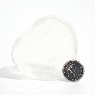 Clear Quartz Heart Bowl beside a Canadian dime for scale, showing the translucent quartz dish at about 2 inches across, on a clean white background. Stonebridge Imports.