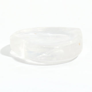 Clear Quartz Heart Bowl seen from the side, showing the shallow carved hollow and the clear quartz walls, on a clean white background. Stonebridge Imports.