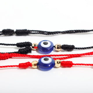 Red and Black — Evil Eye Bracelet with Adjustable Cord 2 Pack, showing the matching red-cord and black-cord string bracelets, each with a blue-and-white evil eye flanked by gold beads, photographed on a clean white background. Stonebridge Imports.