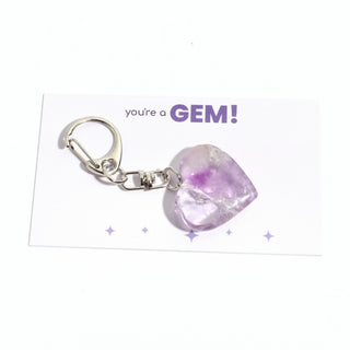 One of the five pale lilac amethyst heart charms from the pack, shown on its "you're a GEM!" gift backing card, hanging from its silver clasp on a clean white background. Stonebridge Imports.