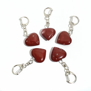 Red Jasper Heart Charm - Pack of 5 - five polished deep red jasper hearts, each on its own silver-tone swivel clasp, arranged on a clean white background. Stonebridge Imports.