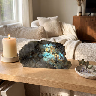 Labradorite Polished Face Cut Base Unique #1 displayed on a wooden home altar shelf beside a lit candle, shown at true size in warm natural light.
