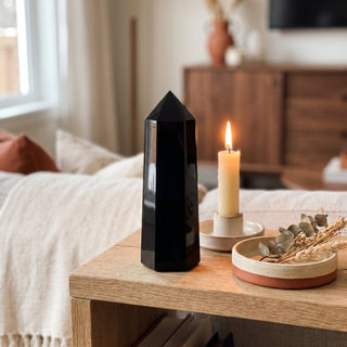 Black Obsidian Generator Unique #11 displayed on a wooden home altar shelf beside a lit candle and dried botanicals, shown at true size in warm natural light.