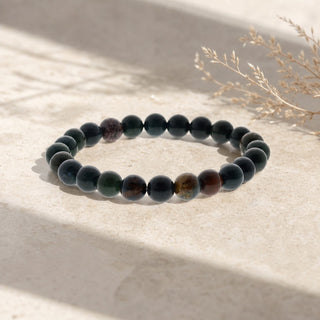 Bloodstone bead bracelet resting on a stone slab