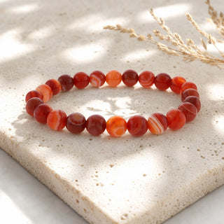 Banded Carnelian bead bracelet resting on a stone slab