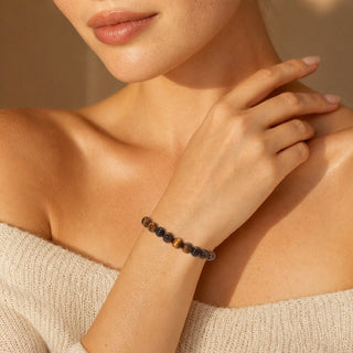 Gold Tiger's Eye bead bracelet worn with the fingertips resting at the collarbone