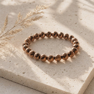 Copper Hematite, Faceted bead bracelet resting on a stone slab