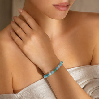 Hemimorphite bead bracelet worn with the fingertips resting at the collarbone