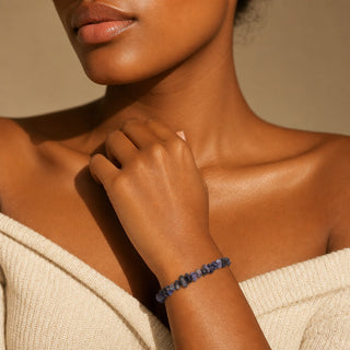 Iolite bead bracelet worn with the fingertips resting at the collarbone
