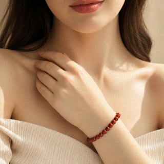 Red Jasper bead bracelet worn with the fingertips resting at the collarbone