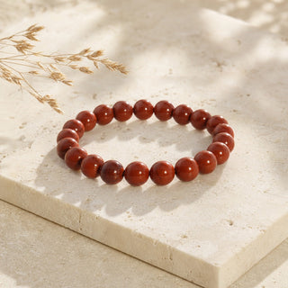 Red Jasper bead bracelet resting on a stone slab
