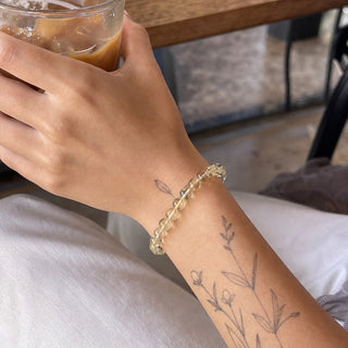 Lemon Quartz bead bracelet worn on a tattooed forearm holding a coffee