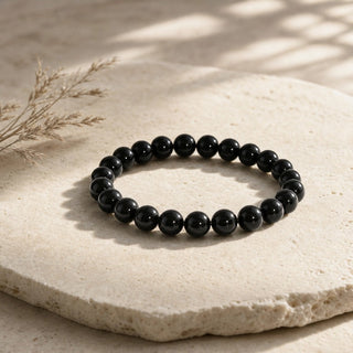 Rainbow Obsidian bead bracelet resting on a stone slab