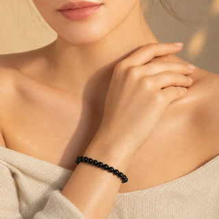 Black Onyx bead bracelet worn with the fingertips resting at the collarbone
