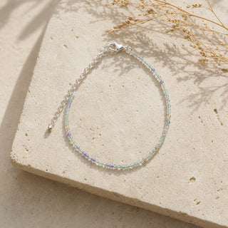Purple & Green Fluorite bead bracelet resting on a stone slab