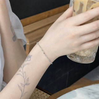 Purple & Green Fluorite bead bracelet worn on a tattooed forearm holding a coffee