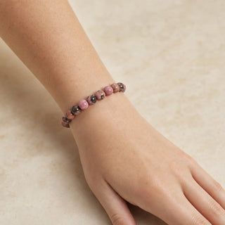 Rhodochrosite bead bracelet worn on the wrist, close-up