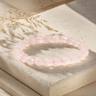 Rose Quartz bead bracelet resting on a stone slab