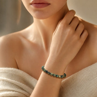 African Turquoise bead bracelet worn with the fingertips resting at the collarbone